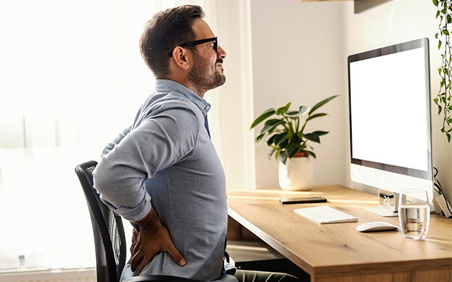 Mann mit R&uuml;ckenschmerzen im B&uuml;ro